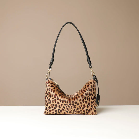 Leopard print crossbody Danilos bag with a black strap on a beige background