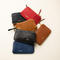A collection of A card case with a zipper coin compartment, made of polished pebble leather, with the letter 'D' visible on the front.