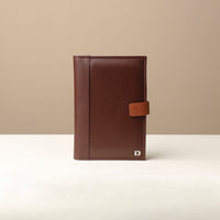 A small brown leather portfolio with a tan trim, featuring a front cover with a snap closure and a visible brand logo.