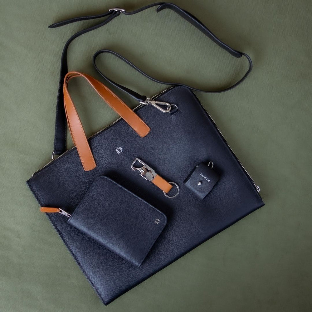Navy blue handbag with brown strap and matching wallet on a green background