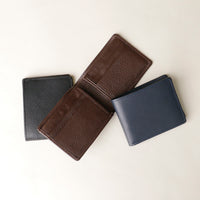Three leather wallets in black, brown, and navy on a light beige background
