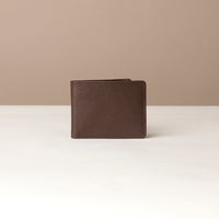 Brown leather wallet on a white surface with a beige background