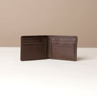 Brown leather wallet open on a white surface with a beige background