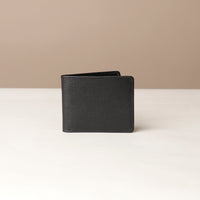 Black leather wallet on a white surface with a beige background