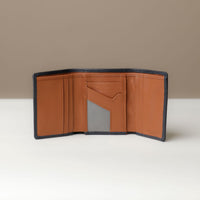 A open trifold wallet in black and tan color, made from pebbled leather with nappa leather interior, with 6 slots for cards and a long comparment for cash, displayed against a neutral background.
