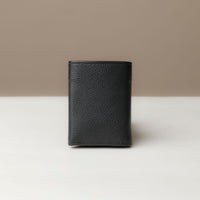 A trifold wallet in black color, made from pebbled leather, displayed against a neutral background. Closed view.