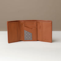 A open trifold wallet in tan color, made from pebbled leather, with nappa leather interior with slots for cards and a long comparment for cash, displayed against a neutral background.