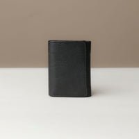 A closed trifold wallet in black color, made from pebbled leather, displayed against a neutral background.