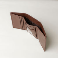 A open trifold wallet in brown color, made from pebbled leather and nappa leather slots for cards, with a long compartment for cash, displayed against a neutral background. Upper view.