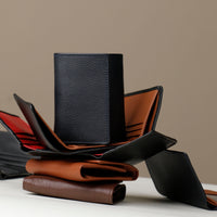 A trifold wallet in dark blue and brown colors with a velvety microsuede lining, displayed in an open and closed position, showing multiple card slots and a full-length bill compartment.