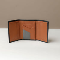 A open trifold wallet in black and tan color, made from pebbled leather with nappa leather interior, with 6 slots for cards and a long comparment for cash, displayed against a neutral background.