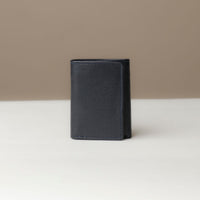 A closed trifold wallet in dark blue color, made from pebbled leather, displayed against a neutral background.