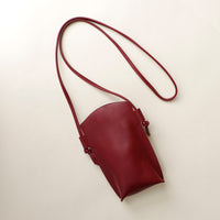 Maroon leather shoulder bag on a light beige background