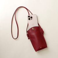 Red phone pouch with a phone inside on a light beige background