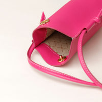Close-up of a pink handbag with gold accents on a light background