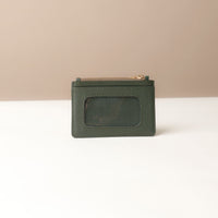 back view of a nappa leather card case nirua in emerald green brown with gold accents over a beige background