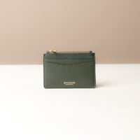 front view of a nappa leather card case nirua in emerald green brown with gold accents over a beige background