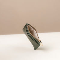 upper view of a open nappa leather card case nirua in emerald green brown with gold accents over a beige background