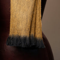 Close-up of a yellow and black scarf on a mannequin against a brown background
