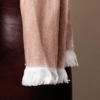 Close-up of a brown scarf with white fringe on a dark background