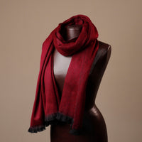 Red scarf with black trim draped over a mannequin against a beige background