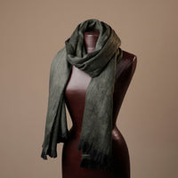 Green scarf draped over a mannequin against a brown background