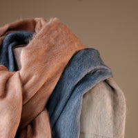 Stack of folded fabric in brown, blue, and beige on a neutral background