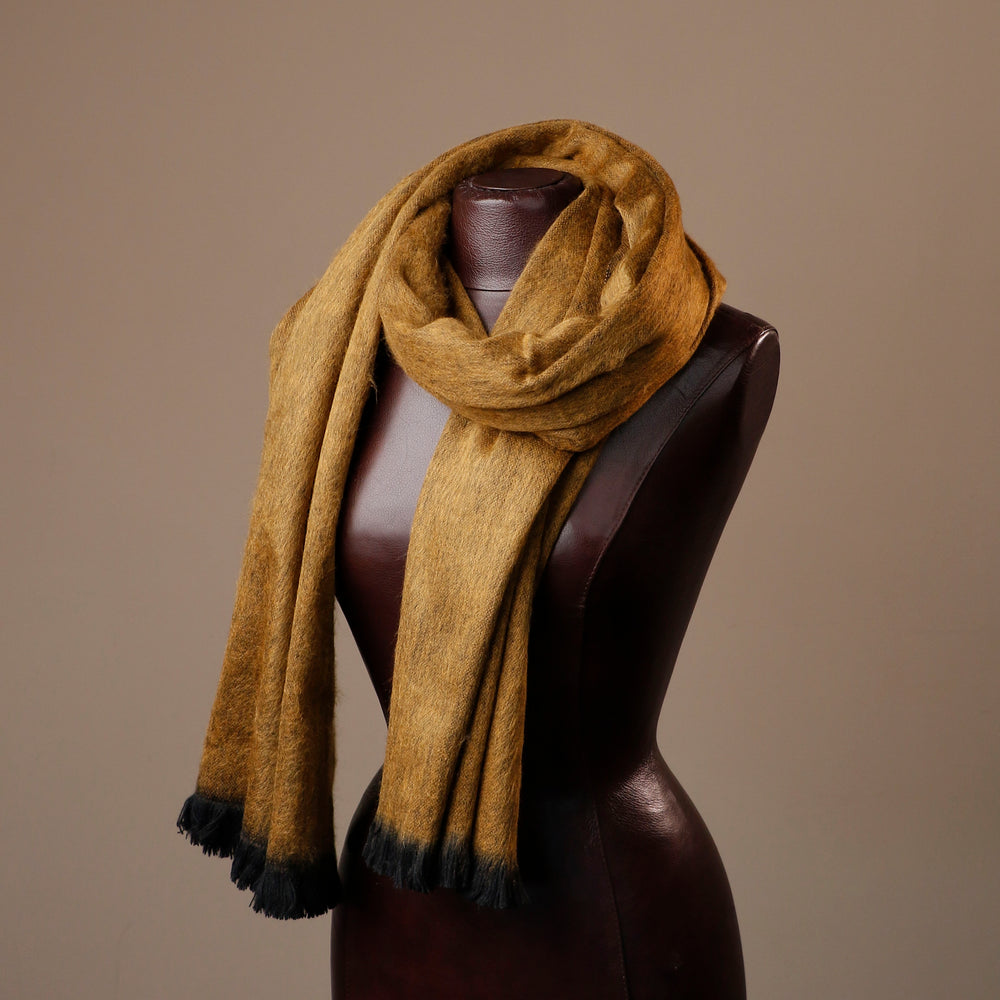 Brown scarf with black tips draped over a mannequin against a brown background
