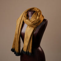 Brown scarf with black tips draped over a mannequin against a brown background
