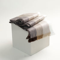 Folded plaid blanket with brown and beige pattern on a white surface