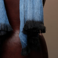 Blue and black scarf with tassels on a neutral background
