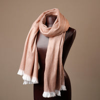 Beige scarf with white trim draped over a mannequin against a brown background