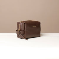 Leather toiletry bag in brown color, displayed against a neutral background.