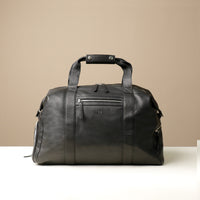 a black leather duffle bag with zippered compartment on the front side.
