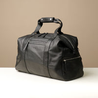 Angled View of a black leather duffle bag with zippered compartment on the front side.