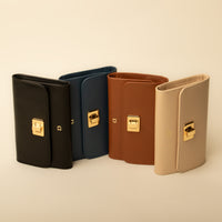 A collection of four tri-fold style wallets in black, blue, brown, and beige colors, each with a high-quality turnlock closure.
