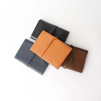 A collection of four leather cable organizers in black, brown, blue, and orange, laid out on a white background.