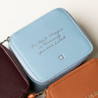 close up view of a small leather Danilos Jewelry Organizer Anushka in light blue with embossed text on a beige background