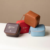 Four stacked small leather Danilos Jewelry Organizer Anushka with embossed text on a beige background