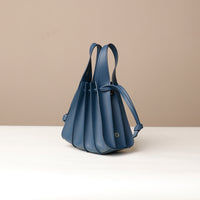 A blue, mini bucket-style leather handbag with pleated details and a drawstring closure, displayed against a neutral background.