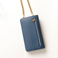 back view of a blue danilos leather multi smartphone alessia with a gold zipper pocket and chain over a beige background