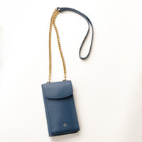 front view of a blue danilos leather multi smartphone alessia with a gold zipper pocket and chain with leather combination over a beige background