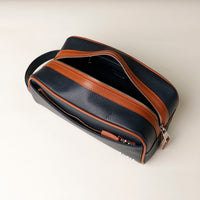 A pebble blue and tan Emmiliano toiletry bag with zipper closure placed against a neutral background. Open view.