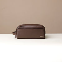 A pebble brown, full-grain leather toiletry bag Emmiliano with a zipper closure, displayed against a neutral background. Front view. 