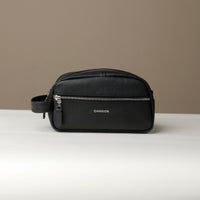 A black toiletry bag 2014 with a silver zipper closure and a handle, with visible brand Danilos, placed against a neutral background. Front view. 