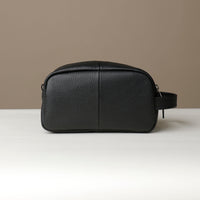 A black toiletry bag 2014 with a silver zipper closure and a handle, with visible brand Danilos, placed against a neutral background. Back view. 