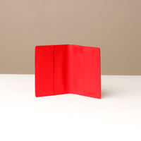 front view of an open red pebble leather passport lovable Danilos on a light surface with a neutral background