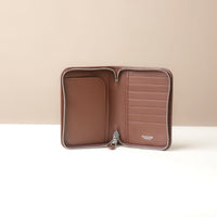Brown leather wallet with a zipper on a beige background