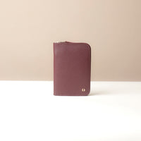 Brown leather wallet with gold zipper on a beige background