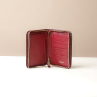 Open red leather wallet with gold zipper on a beige background